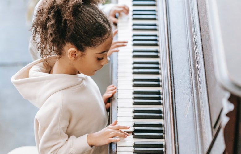 dziewczynka w bluzie z kapturem gra na fortepianie